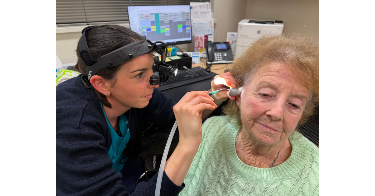 A nurse using microsuction to evacuate the cerumen from the ear of a patient